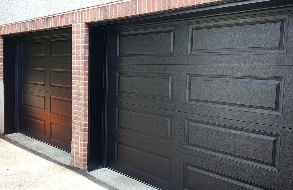 Deux portes de garage foncées à panneaux dans une façade de brique rouge