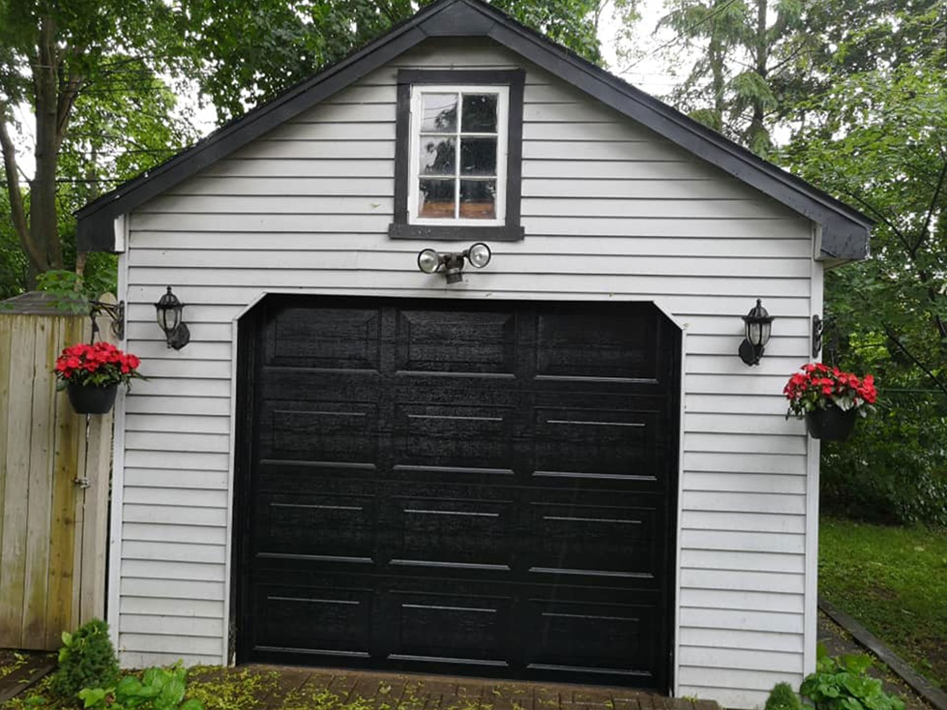 Detached garage with a black door and grey siding