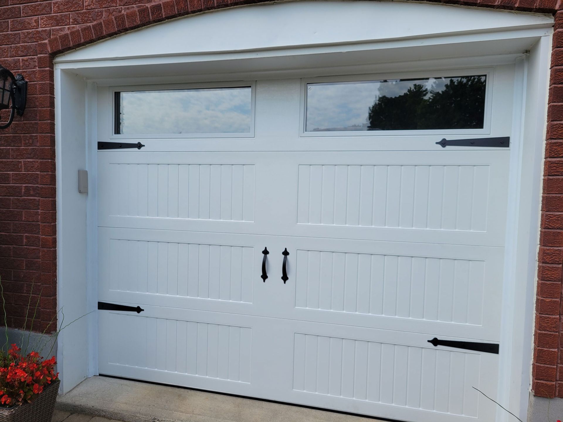 White garage door with two windows, black handles and decorative hinges