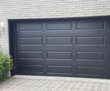 Dark grey garage door in a white brick facade