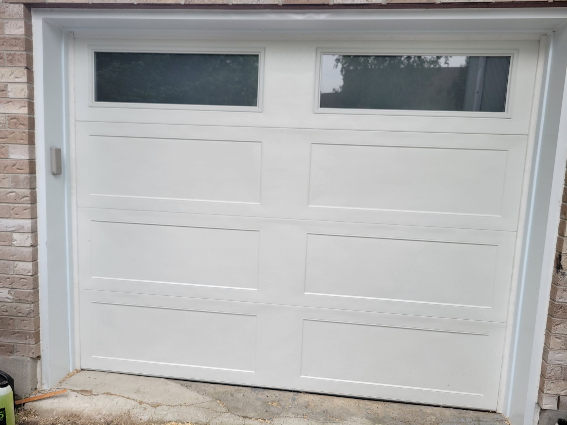 White garage door with rectangular panels and two horizontal windows